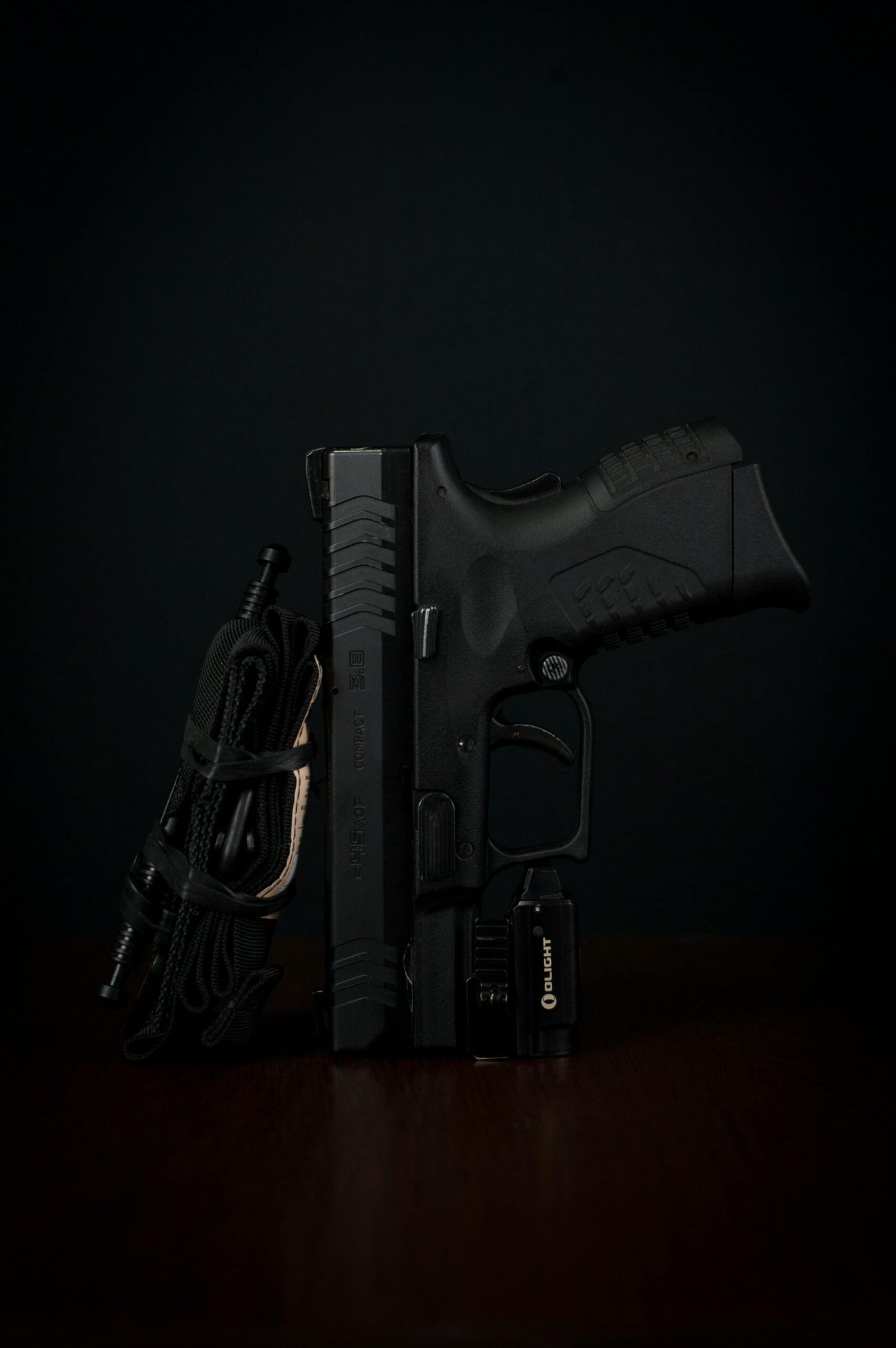 Detailed close-up of a handgun with tactical accessories against a dark backdrop.